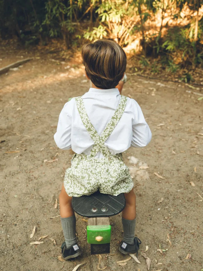 Niño de espaldas con pantalón de tirantes verde con flores blancas Colección Helecho | MICŪ baby